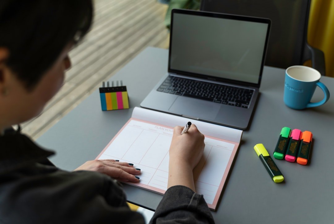person writing at desk with notebook